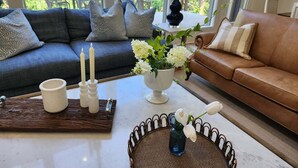 Un salon avec un canapé, une table basse, un vase de fleurs et une lampe.