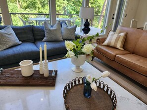 A living room with a sofa, a coffee table, a vase with flowers, and a lamp. - Brand New Family Lake Retreat with Two Living Areas (Greers Ferry)