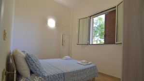 Een slaapkamer met een bed, een raam, een deur en een wandlamp.