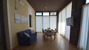 Een woonkamer met een bank, eettafel, stoelen en een televisie.