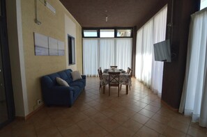 Una sala de estar con sofá, mesa de comedor, sillas y televisor.