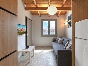 Eine moderne Küche mit Holzbalkendecke, einem weißen Kühlschrank, einem grauen Sofa und einem kleinen Tisch mit einer Schüssel.