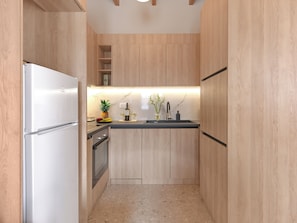 Eine kleine Küche mit Holzausstattung, einem eingebauten Ofen, einer Edelstahl-Spüle und einer Arbeitsplatte mit einer Weinflasche und einer Ananas.