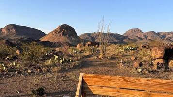 A wooden bench in a desert landscape with mountains in the background.