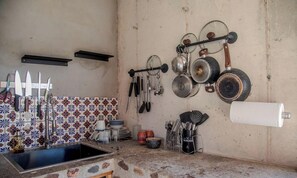 Una cucina con piastrelle a parete, un lavello e diversi utensili e pentole appese al muro.
