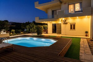 Ein modernes, zweistöckiges Haus mit Swimmingpool, Gartenmöbeln und einem gepflegten Garten.