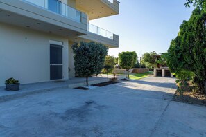 Ein modernes Gebäude mit Flachdach, Balkon und gepflegtem Garten mit kleinen Bäumen und Sträuchern.