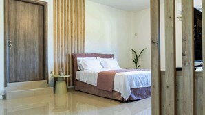 A bedroom with a bed, a wooden door, a bedside table, and a plant. - Olive & Raki Luxury Pool Villa, Crete Garden Oasis (Agioi Theodoroi)