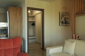 Ein Zimmer mit einem Holzschrank, einem weißen Sofa, einem gerahmten Bild an der Wand und einer Tür zu einem Badezimmer.