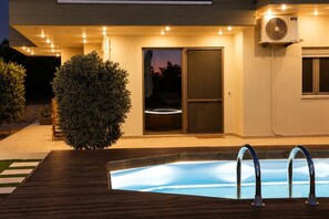 Ein modernes Haus mit Pool, einem großen Busch und einer Klimaanlage.