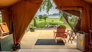 A tent with a wooden deck, a chair, a table, a fan, and a heater.