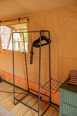 Uma estante de metal com um casaco pendurado, uma janela e um armário verde.