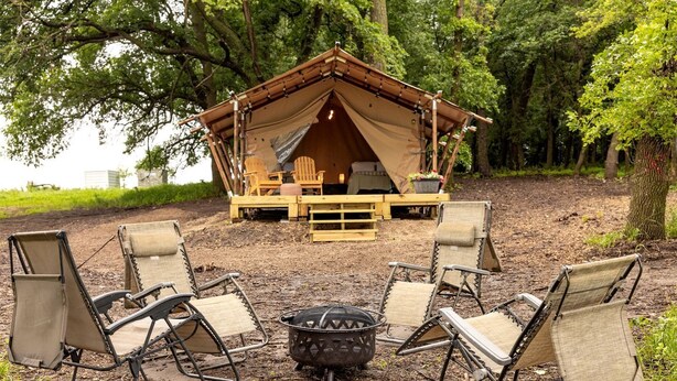 A tented accommodation with a fire pit and outdoor seating.