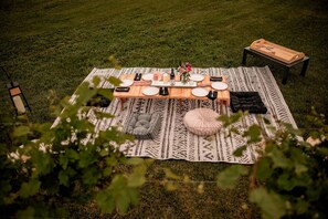 An outdoor dining setup with a table, chairs, and a blanket on a grassy field. - Charming Vineyard Glamping Tent with Wine Tastings near Lake Shetek in Currie, Minnesota (Minneapolis)