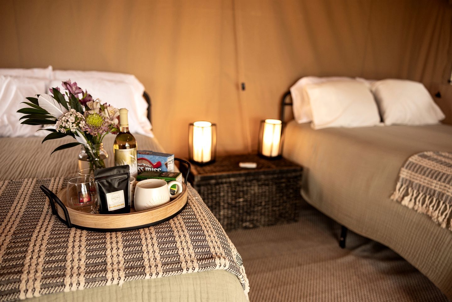 Une chambre d’hôtel avec deux lits, une table de chevet sur laquelle se trouve un plateau avec des articles de toilette, et un vase de fleurs.