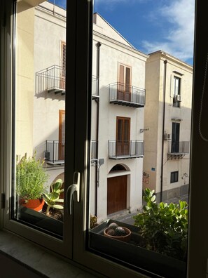 Ein Fenster mit Blick auf ein Gebäude mit Balkonen und einer Tür.