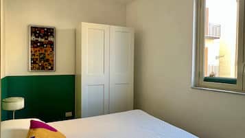 Ein Schlafzimmer mit Bett, Schrank, Fenster und einem Wandbild.