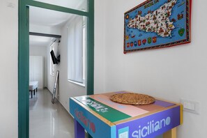 Un couloir avec une table colorée portant l’inscription « siciliano » et une carte de la Sicile accrochée au mur.