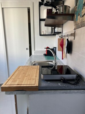 Eine Küche mit Spüle, Schneidebrett und Kaffeemaschine.