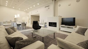 A modern living room with a glass coffee table, sofas, a TV, and a fireplace. - 2BR Villa with Panorama Views - Swing A (Naantali)