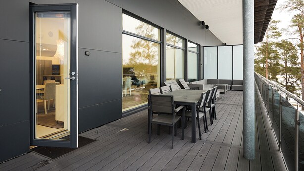 A modern outdoor deck with a dining area, large windows, and a glass door leading to an interior space. - 2BR Villa with Panorama Views - Swing A (Naantali)
