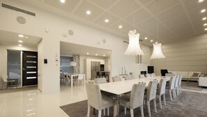 A spacious dining area with a long table and chairs, a kitchen in the background, and a modern ceiling design. - 2BR Villa with Panorama Views - Swing A (Naantali)