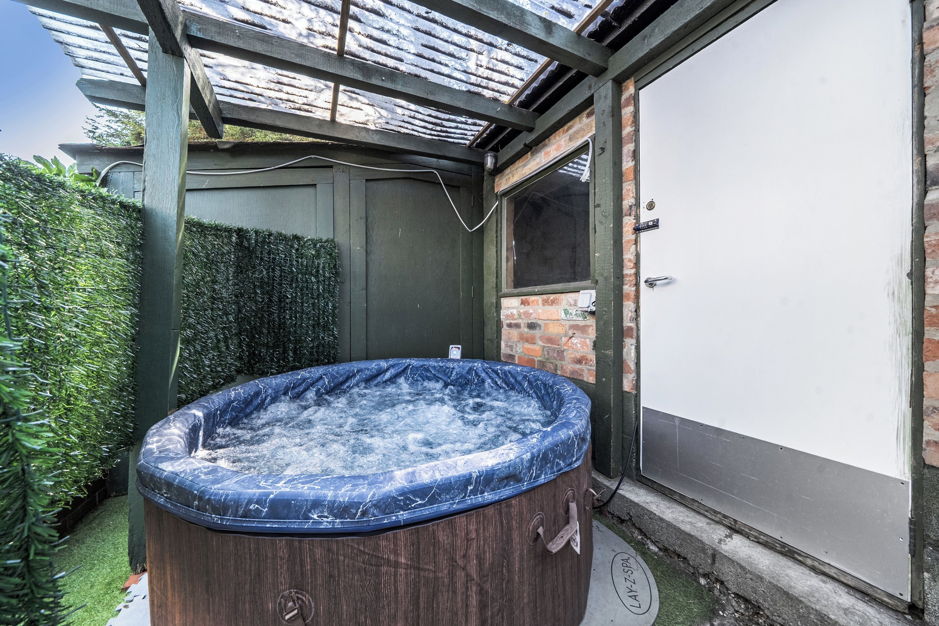 Un jacuzzi con revestimiento de madera, una pared de ladrillo y una puerta a la derecha.