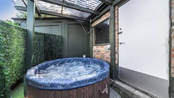 Un jacuzzi con revestimiento de madera, una pared de ladrillo y una puerta a la derecha.