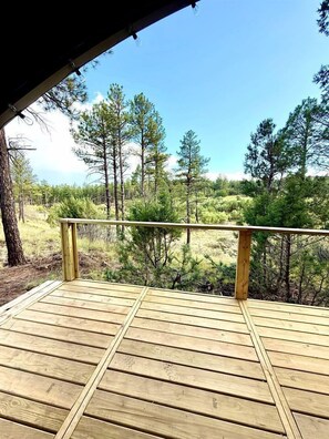Una terraza de madera con barandilla, con vista a un área boscosa.