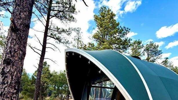 A dome-shaped tent with a wooden deck, chairs, and a table.