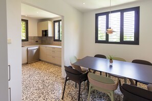Eine moderne Küche mit Essbereich, inklusive Tisch und Stühlen, sowie ein Fenster mit Jalousien.
