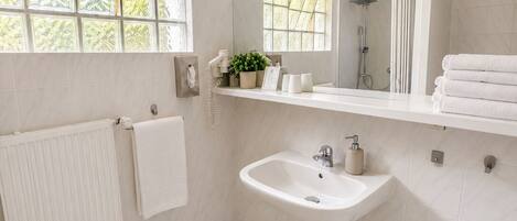 Un baño moderno con un lavamanos blanco, un espejo y una ventana con vistas al verdor.