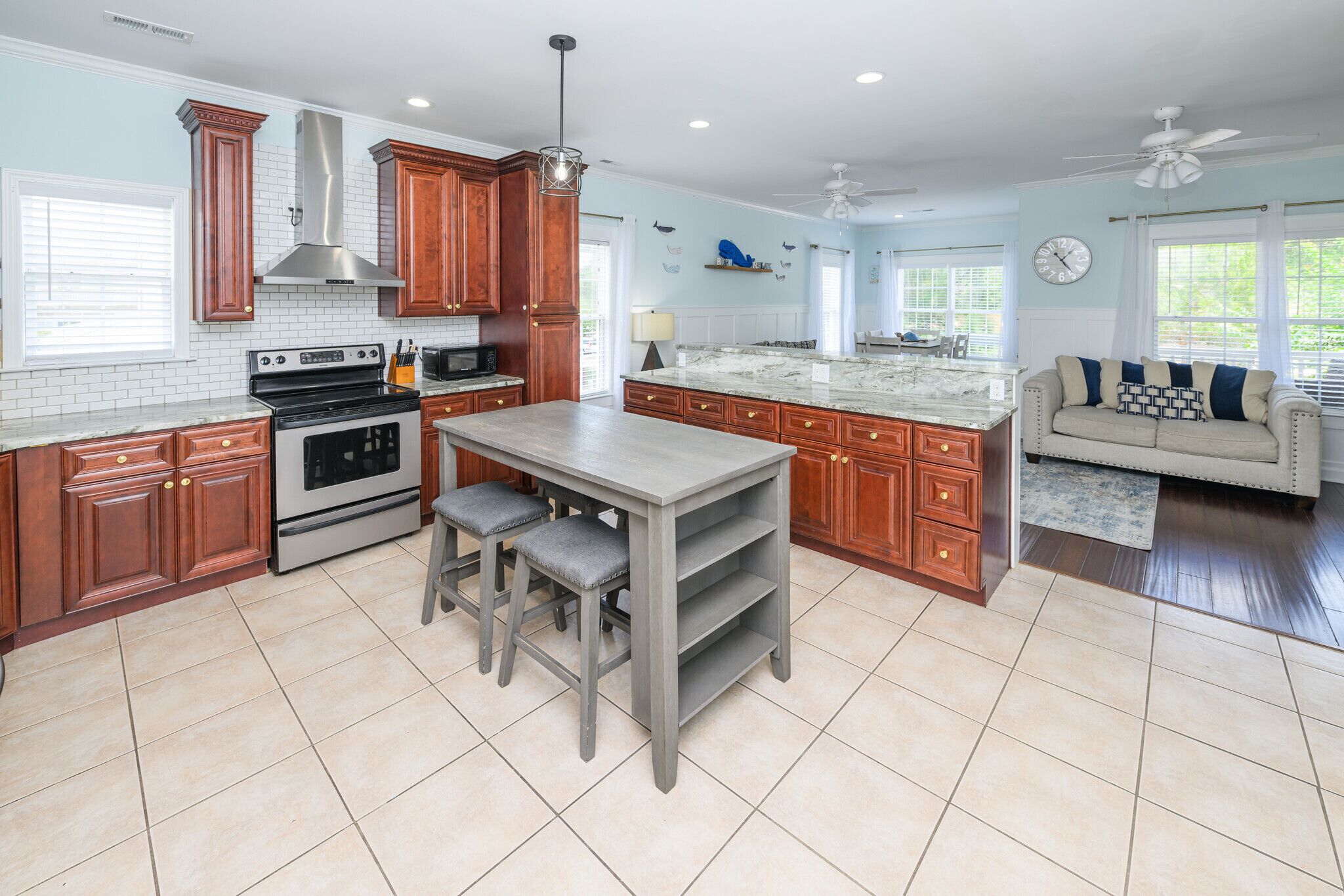 A kitchen with wooden cabinets, a central island, a stove, and a ceiling fan.