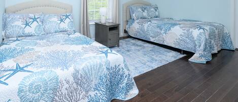 A bedroom with two beds, a nightstand, and a window with blinds.