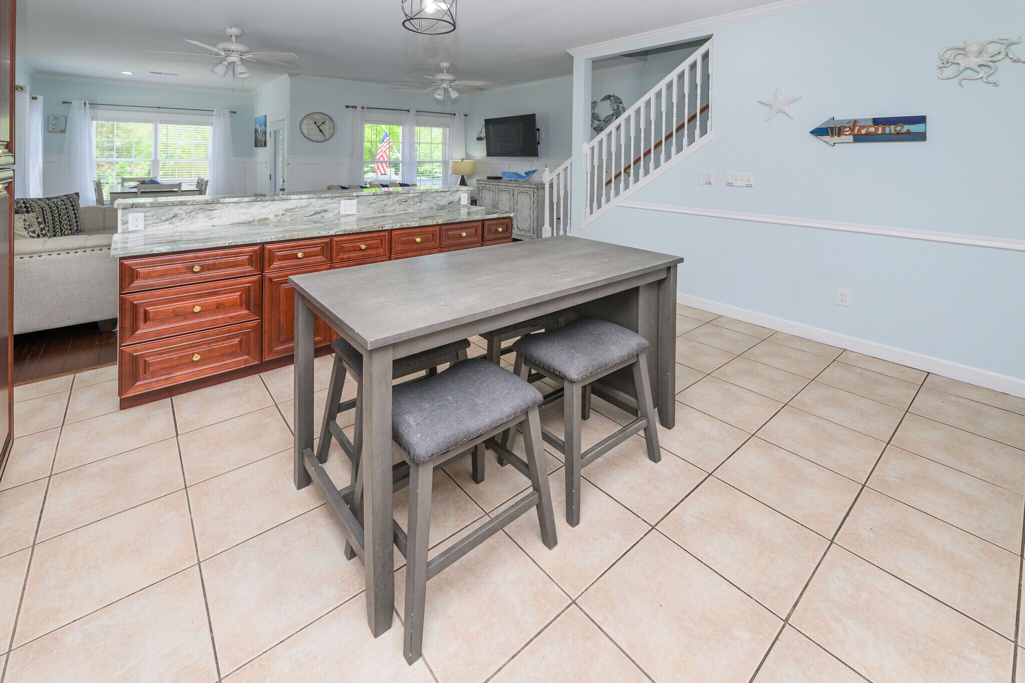 A kitchen with a marble island, wooden cabinets, and a bar area with stools.