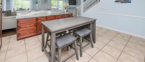 A kitchen with a marble island, wooden cabinets, and a bar area with stools.