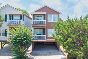 A two-story residential building with a balcony on the upper floor, a covered driveway, and a small tree in the foreground. - Walk to the Beach 4 BR with a Private Pool! Cafe Mocha (Surfside Beach)