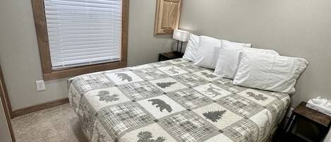 Une chambre à coucher avec un lit, une fenêtre avec des stores, une table de chevet et une lampe fixée au mur.