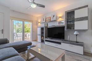 Una sala de estar moderna con sofá, televisor y una mesa de centro de vidrio.