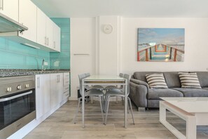 Eine moderne Küche mit weißen Schränken, einem Edelstahlbackofen und einer türkisblauen Spritzschutzwand.