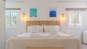 A bedroom with a large bed, two wall-mounted lights, a headboard, and two framed pictures on the wall. - Charming 1-bedroom Apartment With Ocean Views in Costa Adeje (Adeje)