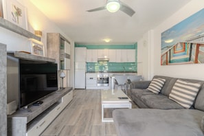 Uma sala de estar moderna com TV de tela plana, sofá e mesa de centro.