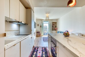 Een moderne keuken met marmeren aanrechtbladen, een centraal eiland en uitzicht naar buiten.