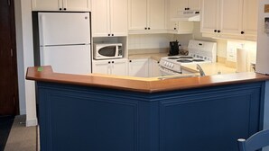 A kitchen with white cabinets, a wooden countertop, a built-in microwave, a stove, and a refrigerator. - Heart of Tremblant - Johanssen, Place St. Bernard (Mont-Tremblant)