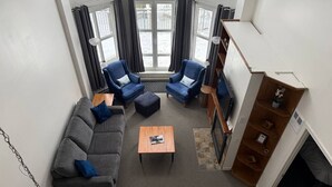 A modern living room with a gray sofa, two blue armchairs, a wooden coffee table, and a fireplace. - Heart of Tremblant - Johanssen, Place St. Bernard (Mont-Tremblant)