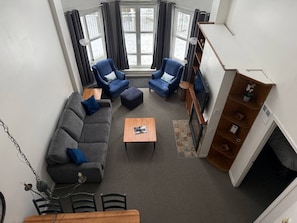 Ein modernes Wohnzimmer mit einem grauen Sofa, zwei blauen Sesseln, einem Holztisch und einem Kamin.