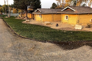 Une rangée de chalets en rondins, avec une pelouse bien entretenue et un chemin de gravier.