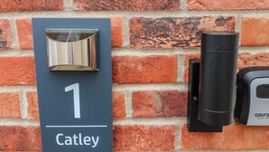 A house number sign with a mailbox and a black cylindrical object, likely a mail slot, on a brick wall. - Walcott Lodges - Catley (Lincoln)