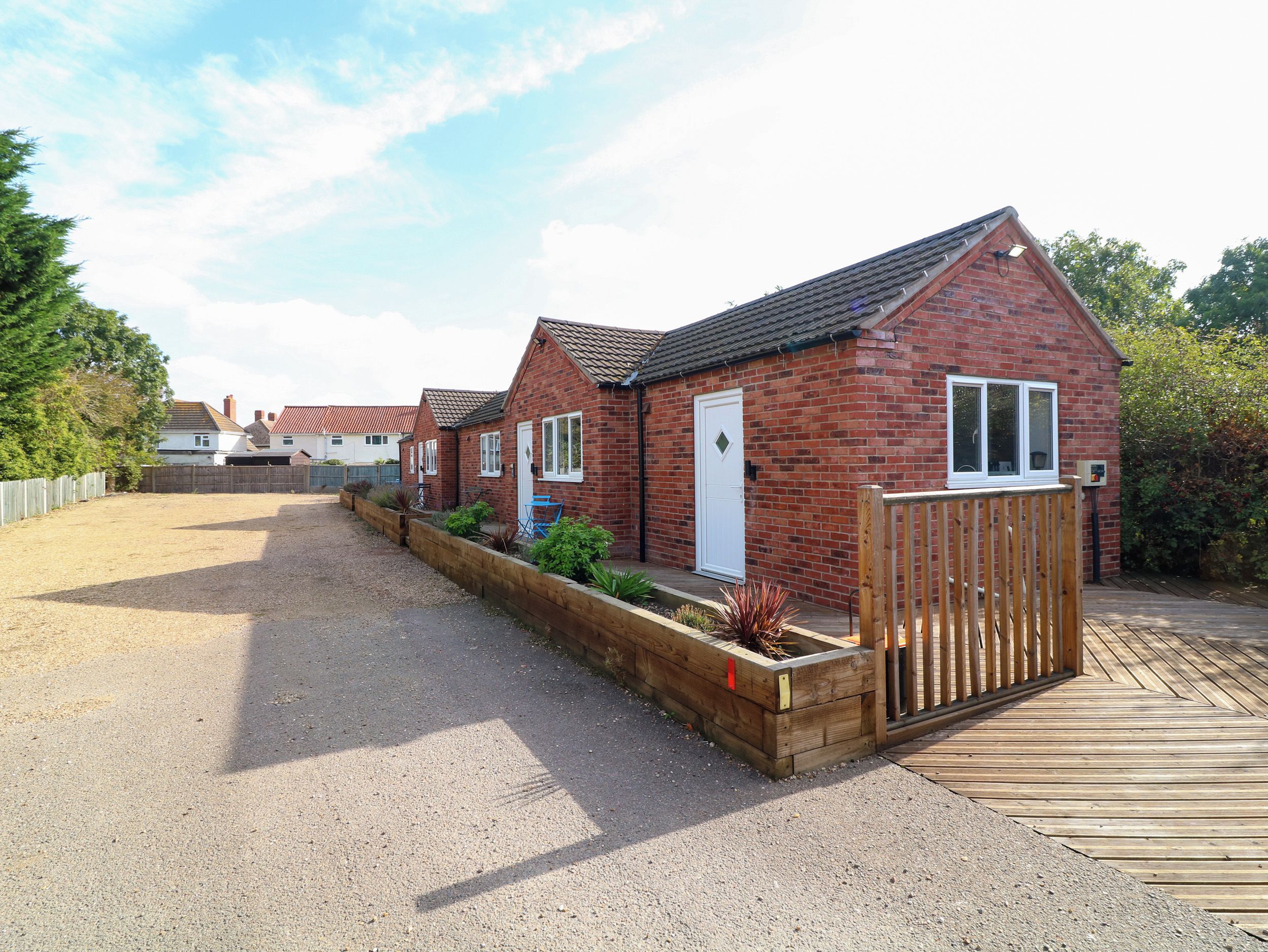 A row of brick houses with a gravel driveway and wooden fences.