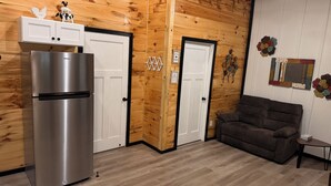 A kitchen with a stainless steel refrigerator, wooden cabinets, and a brown sofa.